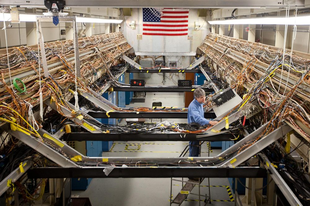 Long bay lined with massive bundled cable runs, one man working at a rack mid-frame