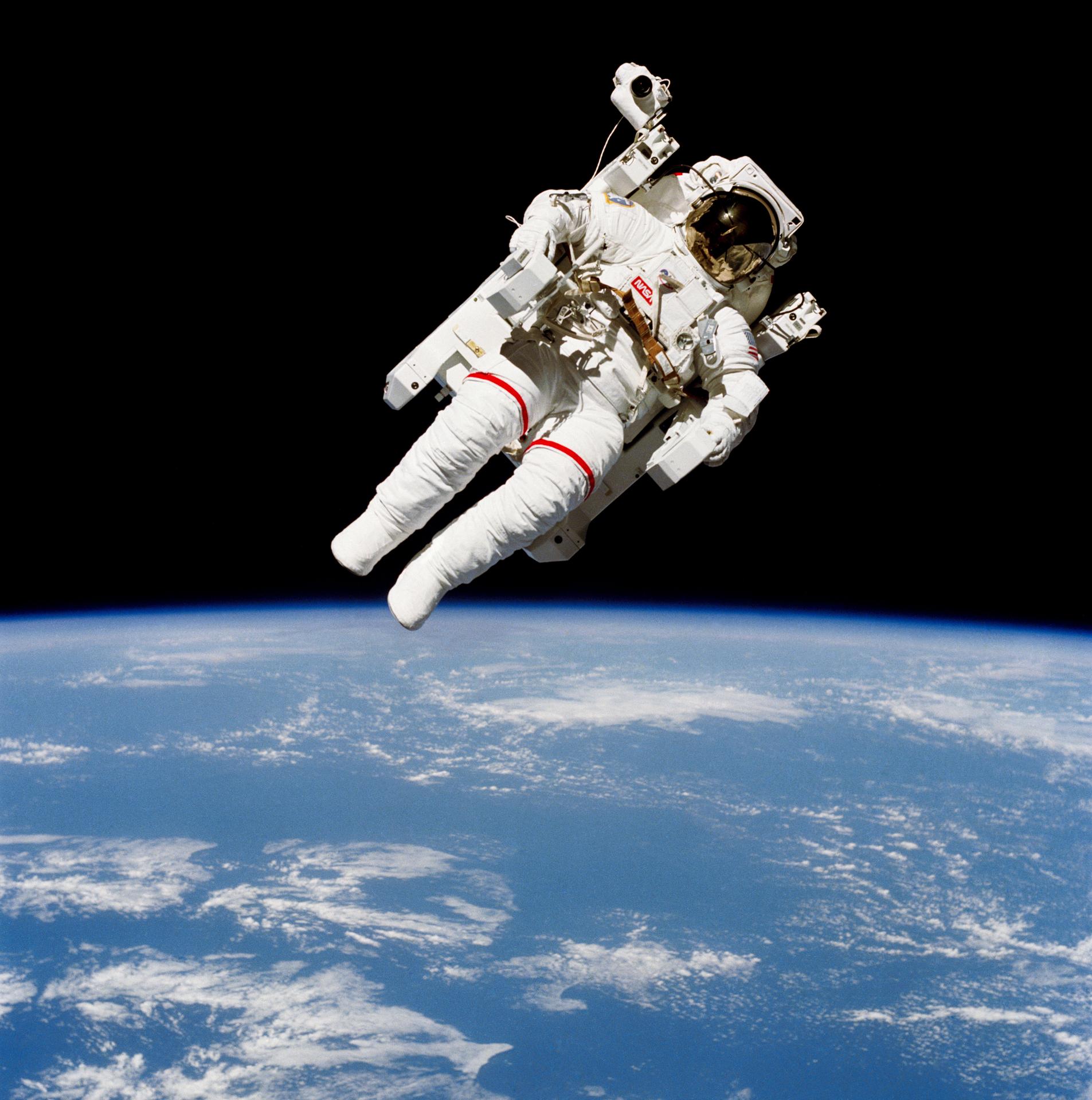 Lone white-suited figure on a backpack thruster unit, untethered above the blue Earth