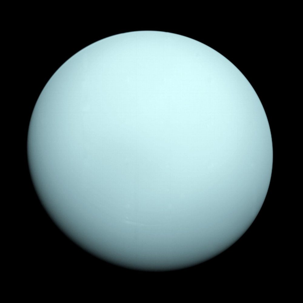 A featureless pale blue-green disc, almost without markings, against black