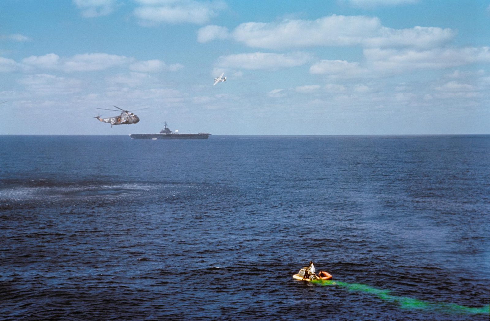A Gemini capsule and green dye marker at sea, a helicopter and carrier beyond