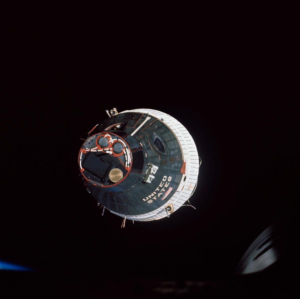 A Gemini spacecraft head-on in black space, hatches and United States lettering visible