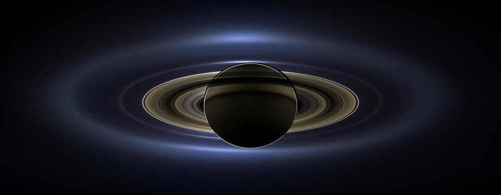 A dark globe in silhouette, its rings glowing in a wide halo of scattered light