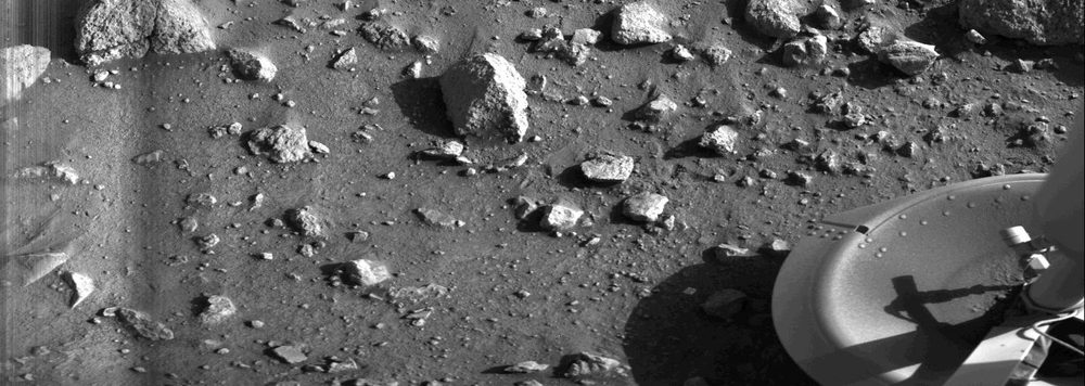 Monochrome scatter of angular rocks across a level plain, hard shadows to one side