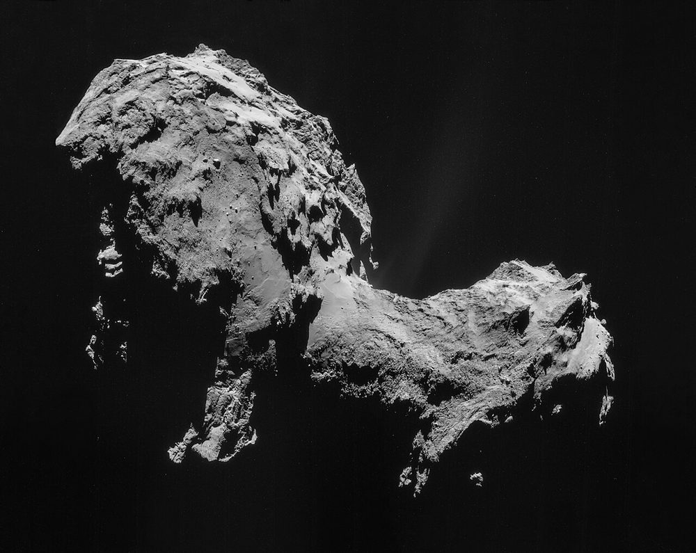 Two-lobed grey nucleus, rough and dust-covered, a faint jet rising from the neck