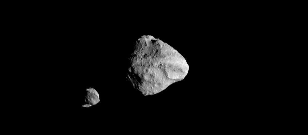 Two grey rocks against black, one large and angular, a much smaller one beside it