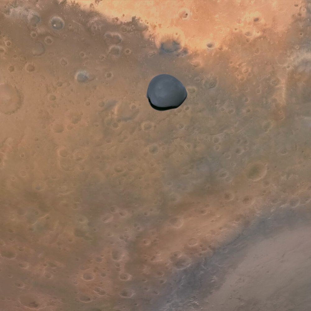 Small grey rounded moon set against wide orange cratered ground below it