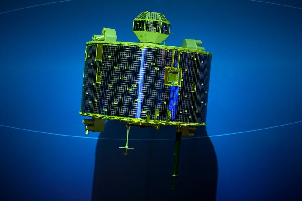 Drum-shaped body covered in solar cells, a small faceted box on top, against blue