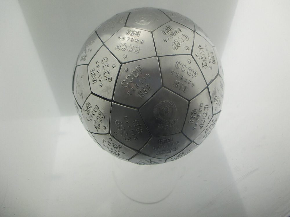 Football-like ball of engraved metal plates, lit against a plain white background