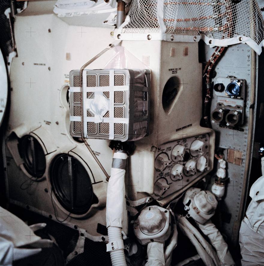 Square canister taped to a cabin panel with a plastic bag and corrugated hose attached