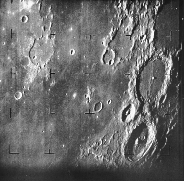 Grainy monochrome view of cratered terrain overlaid with a grid of black reticle crosses