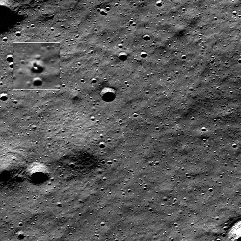 Grey cratered terrain with a white-bordered inset enlarging a small bright object